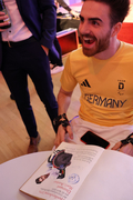 Moritz Brückner sitzt strahlend vor dem Golden Buch des Landkreises Unterallgäu. Darin befindet sich ein handgemaltes Bild von ihm, das er gerne signierte. 
